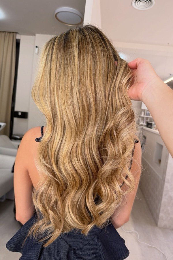 Cabelo comprido loiro dourado em ondas, visto de costas, no salão