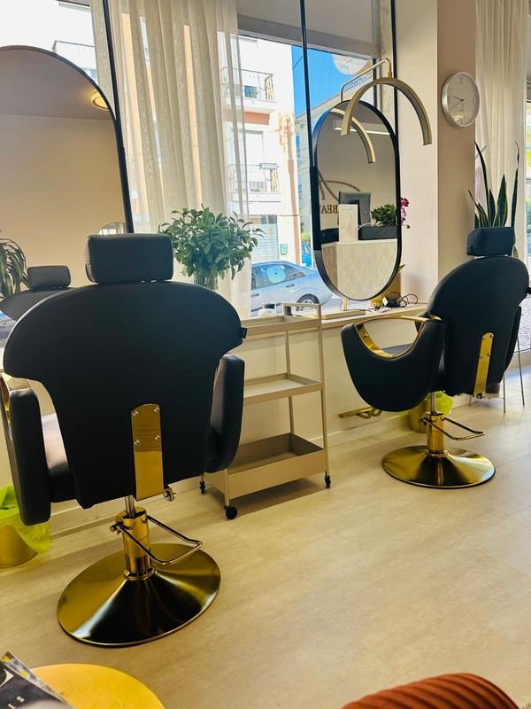 Postos de cabeleireiro do Amalfi Beauty Hair com cadeiras em preto e dourado, espelhos ovais e luz natural das janelas.