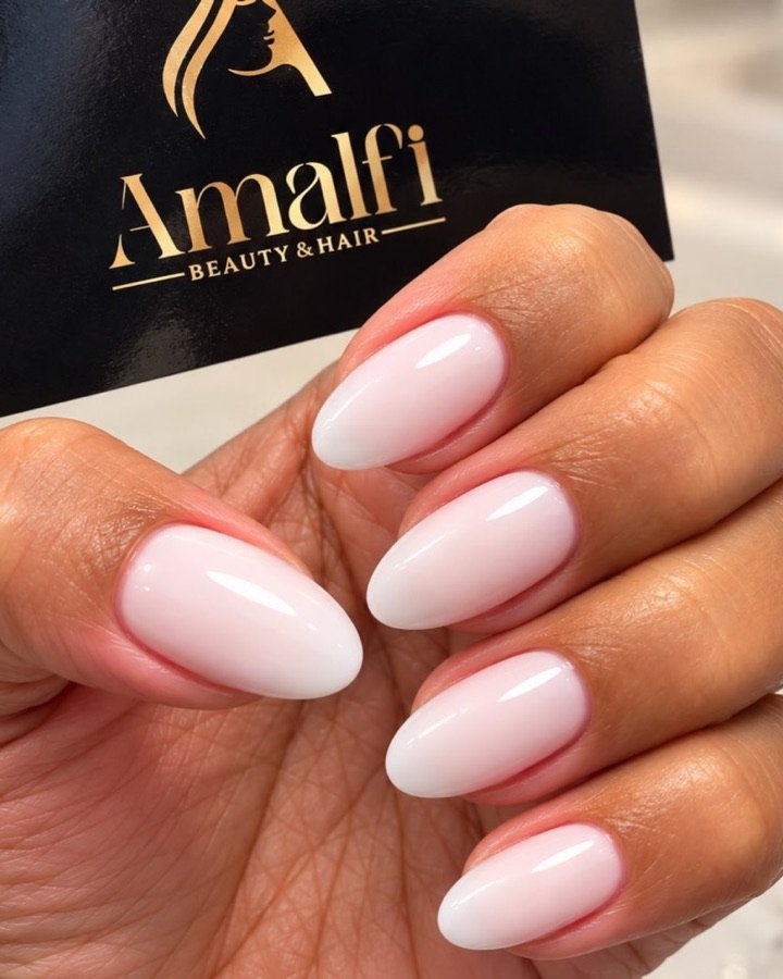 Mão com unhas amendoadas em gel rosa leitoso a segurar um cartão Amalfi
